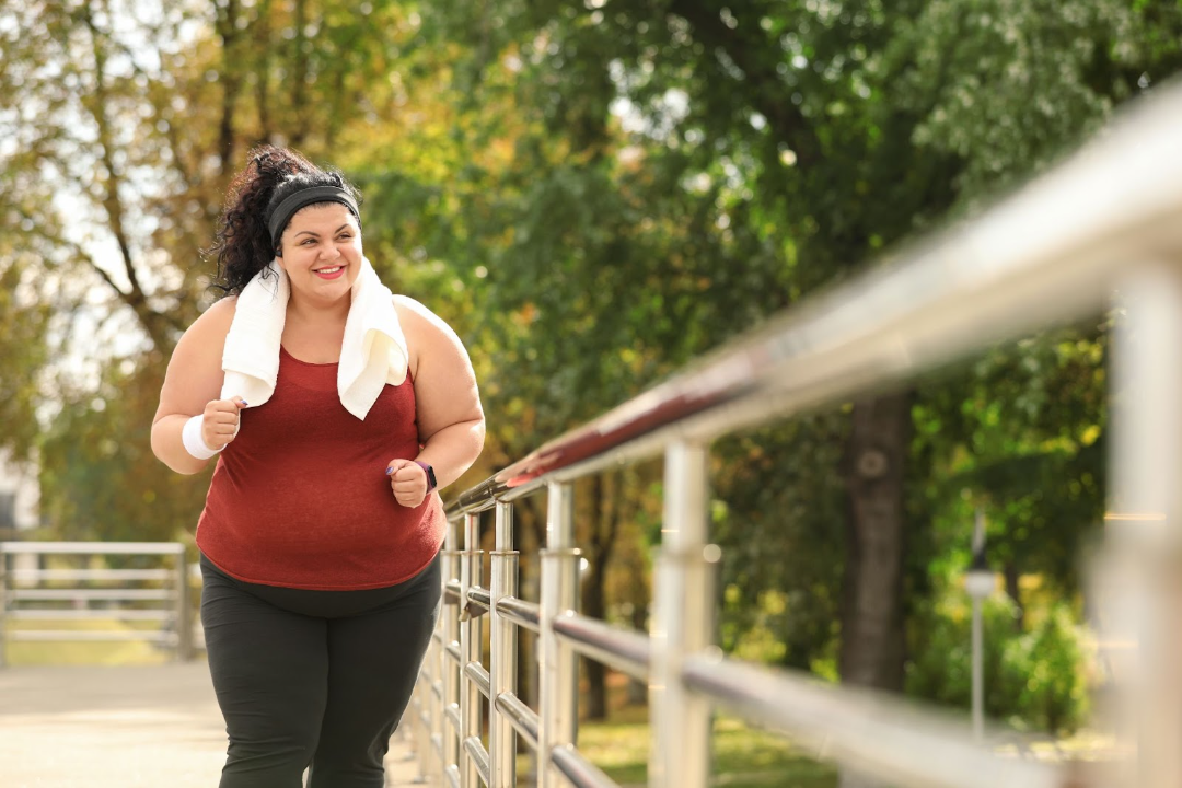 Woman wearing a red shirt with white towel over her neck on a run to try and lose weight